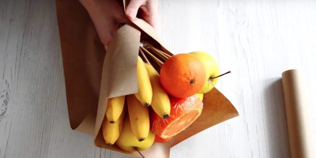 Положите букет на другой прямоугольник бумаги и снова заверните низ